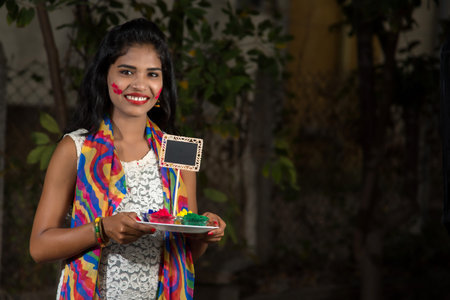 Young girl holding small board and powdered color on the occasion of Holi festival.の写真素材