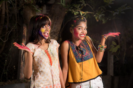 Portrait of happy young girls having fun with colorful powder at Holi festival of colorsの写真素材