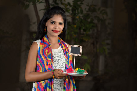 Young girl holding small board and powdered color on the occasion of Holi festival.の写真素材