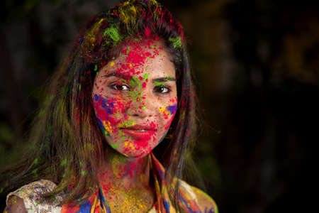 Portrait of a happy young girl with a colorful face on the occasion of Holi color festival.の写真素材