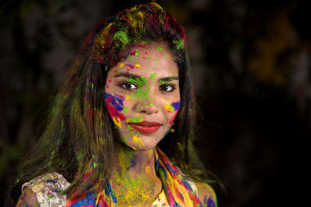 Portrait of a happy young girl with a colorful face on the occasion of Holi color festival.の写真素材