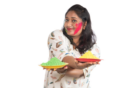 Beautiful young girl holding powdered color in plate on the occasion of Holi festival.の写真素材