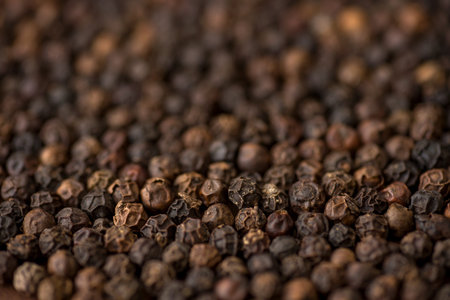 Close up of black pepper or peppercorns as background on wooden background.