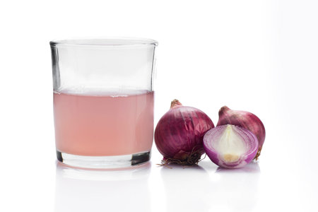 Medicinal Onion juice/syrup in a glass with fresh red onions on a white backgroundの写真素材