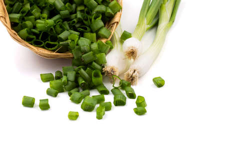 Fresh ripe green spring onions (shallots or scallions) with chopped onions in basket on white backgroundの写真素材