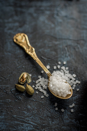 Cardamom with sugar in a spoon on a textured background.