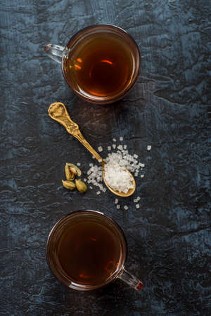 A cup of tea and cardamom with sugar in a spoon on a textured background.の写真素材