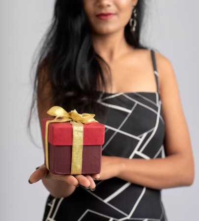 Portrait of a pretty young girl posing with gift box on grey background.の写真素材