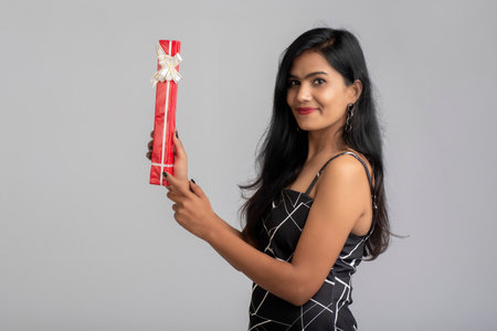 Portrait of a pretty young girl posing with gift box on grey background.の写真素材