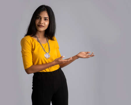 Portrait of a successful cheerful young girl holding and presenting something on hand with a happy smiling face.の写真素材