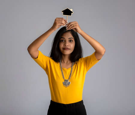 A young girl or businesswoman holding a little cutout board and posing on a gray background.の写真素材