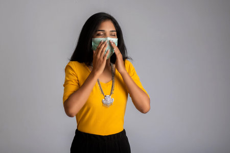 woman wearing a medical mask feeling sick or ill, having a fever.