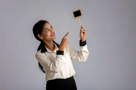 young woman or business woman holding a little cutout board in her hands on a gray background.の写真素材
