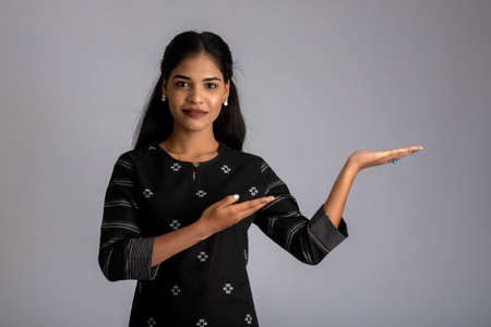 Beautiful girl holding and presenting something in the hand with a happy smiling face.の写真素材