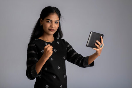 Young Indian girl using a mobile phone or smartphone on gray backgroundの写真素材