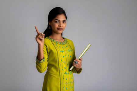 Pretty young girl posing with the book on grey background