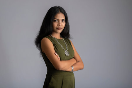 Portrait of a beautiful, smiling, emotional young woman posing with hands-folded on gray background.