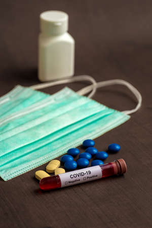 Tube containing a blood sample for testing to the presence of coronavirus / COVID-19 with Mask and medicine tablet.の写真素材