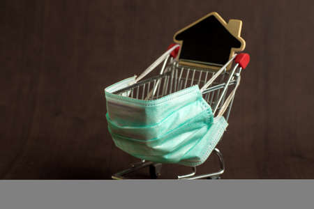 Supermarket cart for shopping. The trolley is wearing a medical mask. virus control concept. Creative idea for an online pharmacy, online drug sale.の写真素材