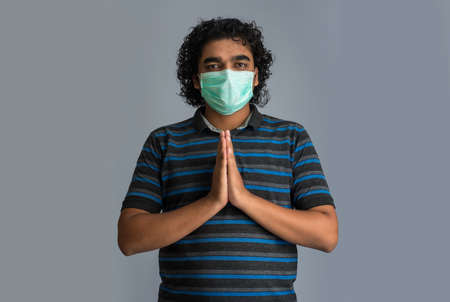 Young man doing Namaste. New greeting to avoid the spread of virus instead of greeting with a hug or handshake. Yoga practice for mental balance.の写真素材