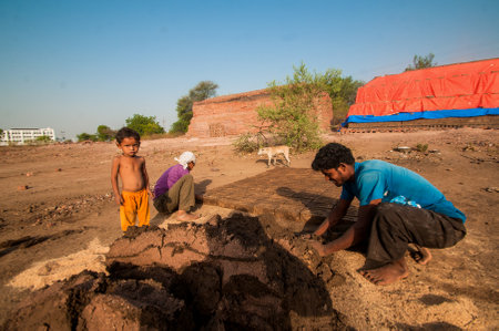 AMRAVATI, MAHARASHTRA - MAY 24, 2018: Unidentified Indian workers making bricks of clay by hand in the factory or field.のeditorial素材