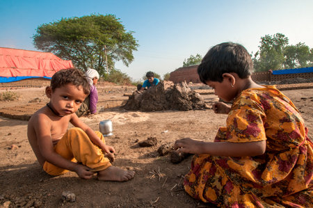AMRAVATI, MAHARASHTRA - MAY 24, 2018: Unidentified Indian kids of workers helping to make in traditional bricks by hand in the brick kiln or factory.のeditorial素材