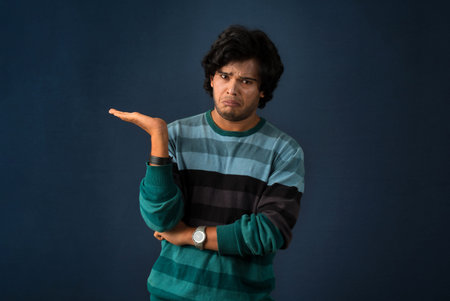 Portrait of a successful cheerful young man holding and presenting something on hand with a happy...