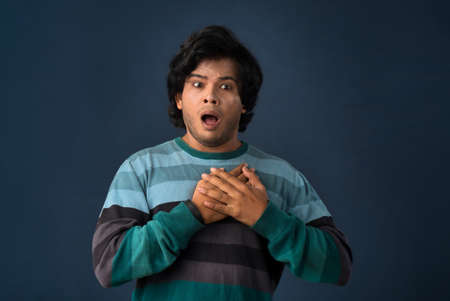 Unhappy young man having a heart attack or heartache over gray background. People, healthcare and health problem concept.の写真素材