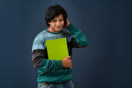 Young happy man holding and posing with the book on background.の写真素材
