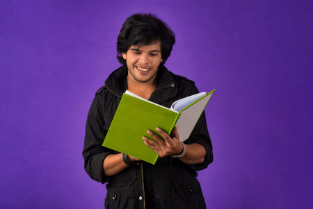 Young happy man holding and posing with the book on background.の写真素材