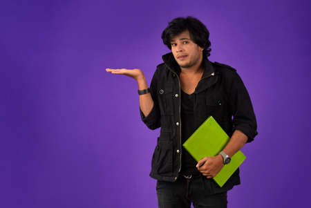 Young happy man holding and posing with the book on background.の写真素材