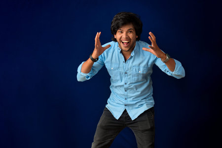 Young handsome man over dark background afraid and shocked with surprise and amazed expression, fear and excited face.の写真素材