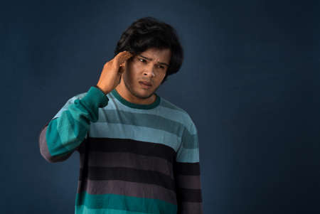 Portrait of young man stress or having the pain of a headache on a grey background.の写真素材