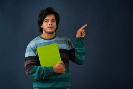 Young happy man holding and posing with the book on background.の写真素材