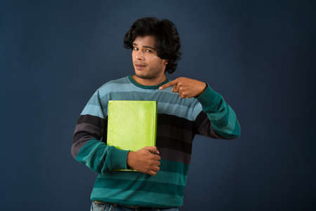 Young happy man holding and posing with the book on background.の写真素材