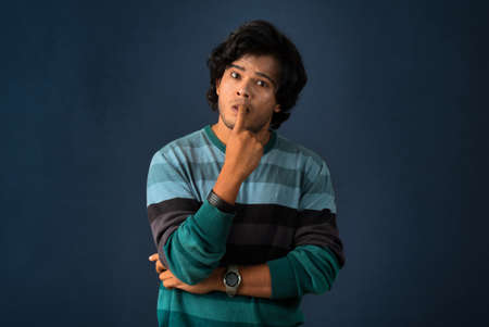 Portrait of a young man thinking on a dark backgroundの写真素材
