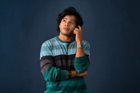 Portrait of a young man thinking on a dark backgroundの写真素材