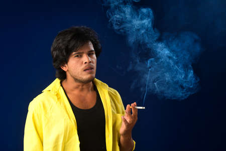 A young man smoking a cigarette and making a lot of smoke around.の写真素材