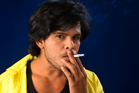 A young man smoking a cigarette and making a lot of smoke around.の写真素材