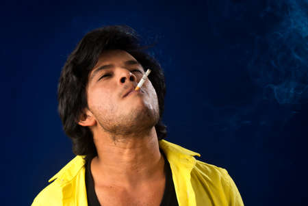 A young man smoking a cigarette and making a lot of smoke around.の写真素材