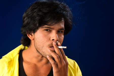 A young man smoking a cigarette and making a lot of smoke around.の写真素材