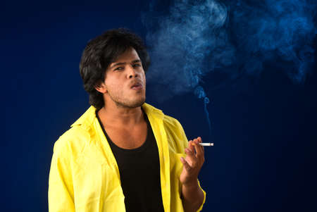 A young man smoking a cigarette and making a lot of smoke around.の写真素材