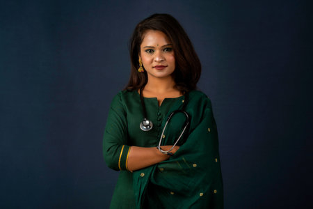 A smiling female doctor wearing a stethoscope on her shoulders looking at the camera on gray background.の写真素材