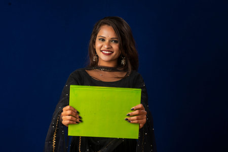Pretty young girl posing with book on blue background