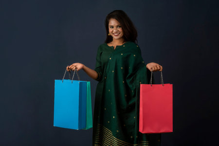 Beautiful Indian young girl or woman holding and posing with shopping bags on a dark background