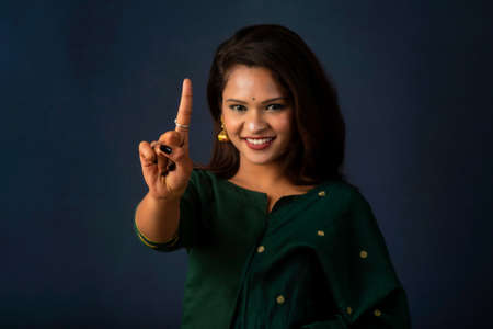 Portrait of a successful cheerful young girl presenting something with a fingers with a happy smiling face.の写真素材
