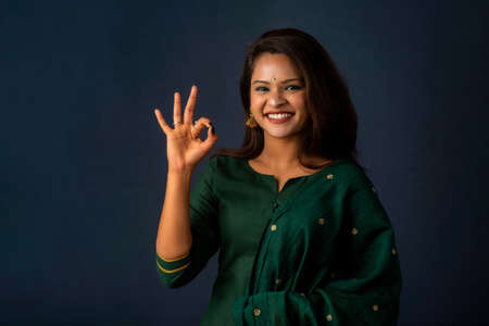 Young smiling girl showing ok sign or thumbs up on a grey backgroundの写真素材