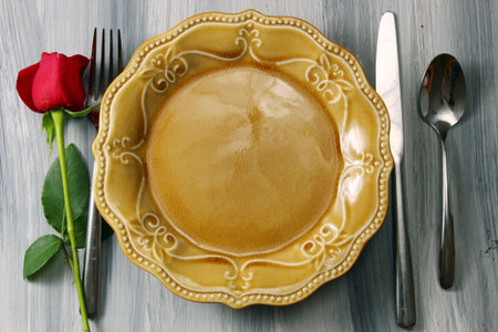 A romantic table setting with a Rose bud on a rustic wooden textured background with copy space.