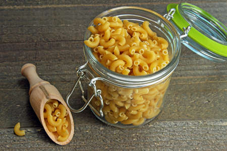 Elbow pasta in a jar on wooden background.の写真素材