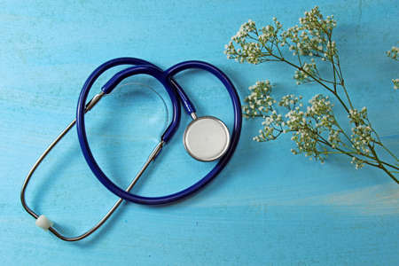 A blue stethoscope with white flowers on blue  background with copy space.の写真素材